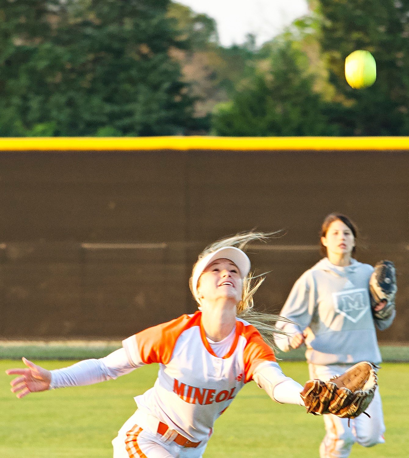Emily Wiley of Mineola chases a fly ball but the gusty winds pushed it away from her. [see more senior night action]